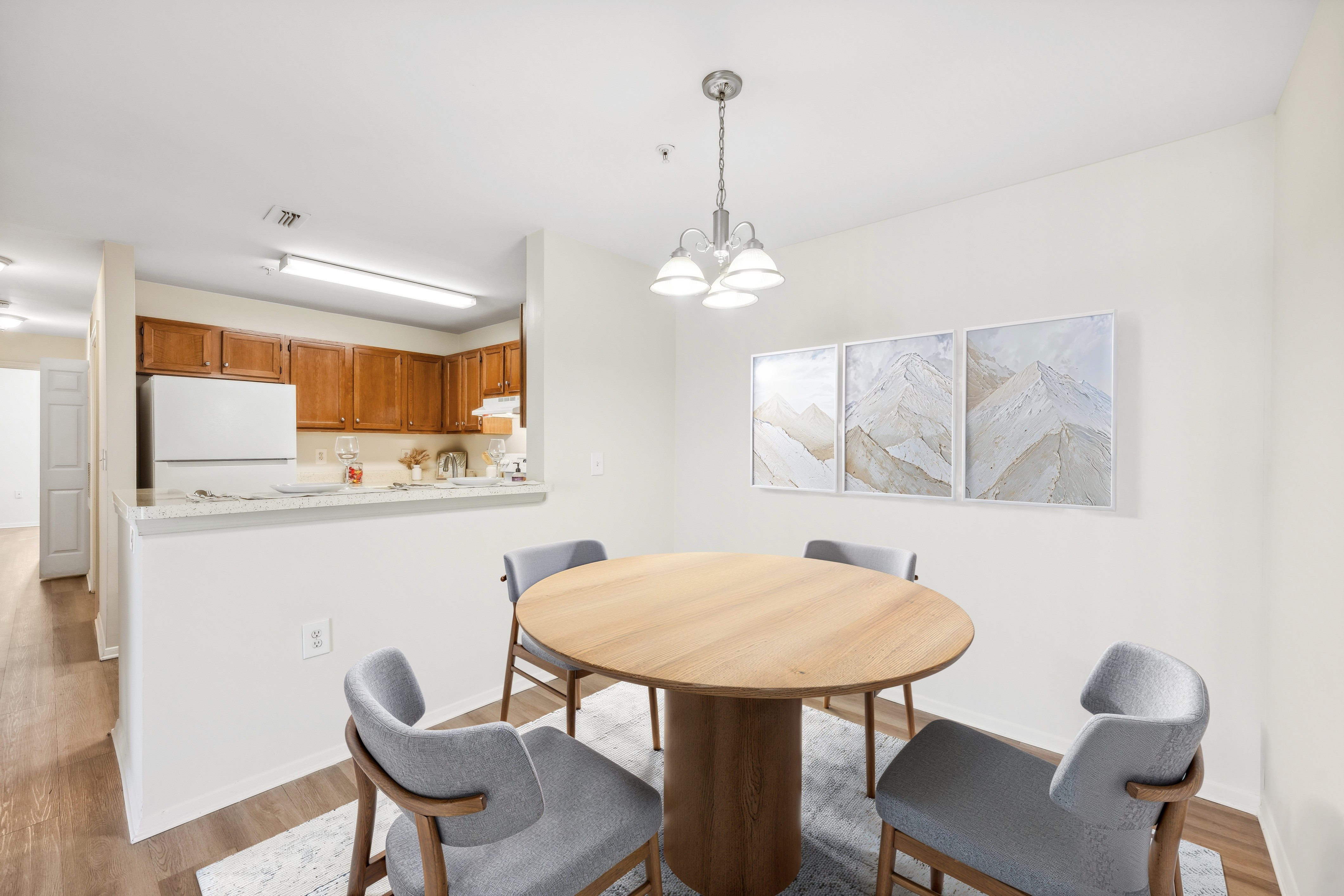 A dining room with a round table and grey chairs.